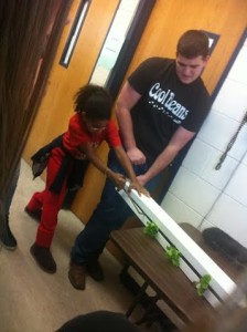 A Maize High School student helps a younger middle school student plant a ZipGrow tower.