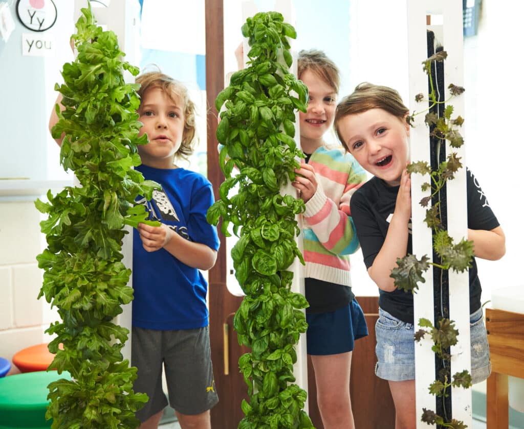 3 children holding ZipGrow Towers with plants in them